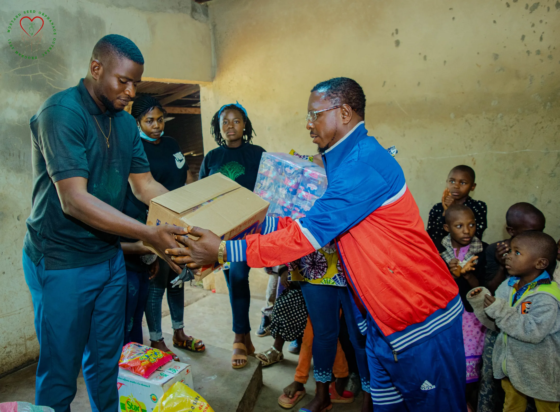 A community volunteer hands a box to a family during an outreach gathering.